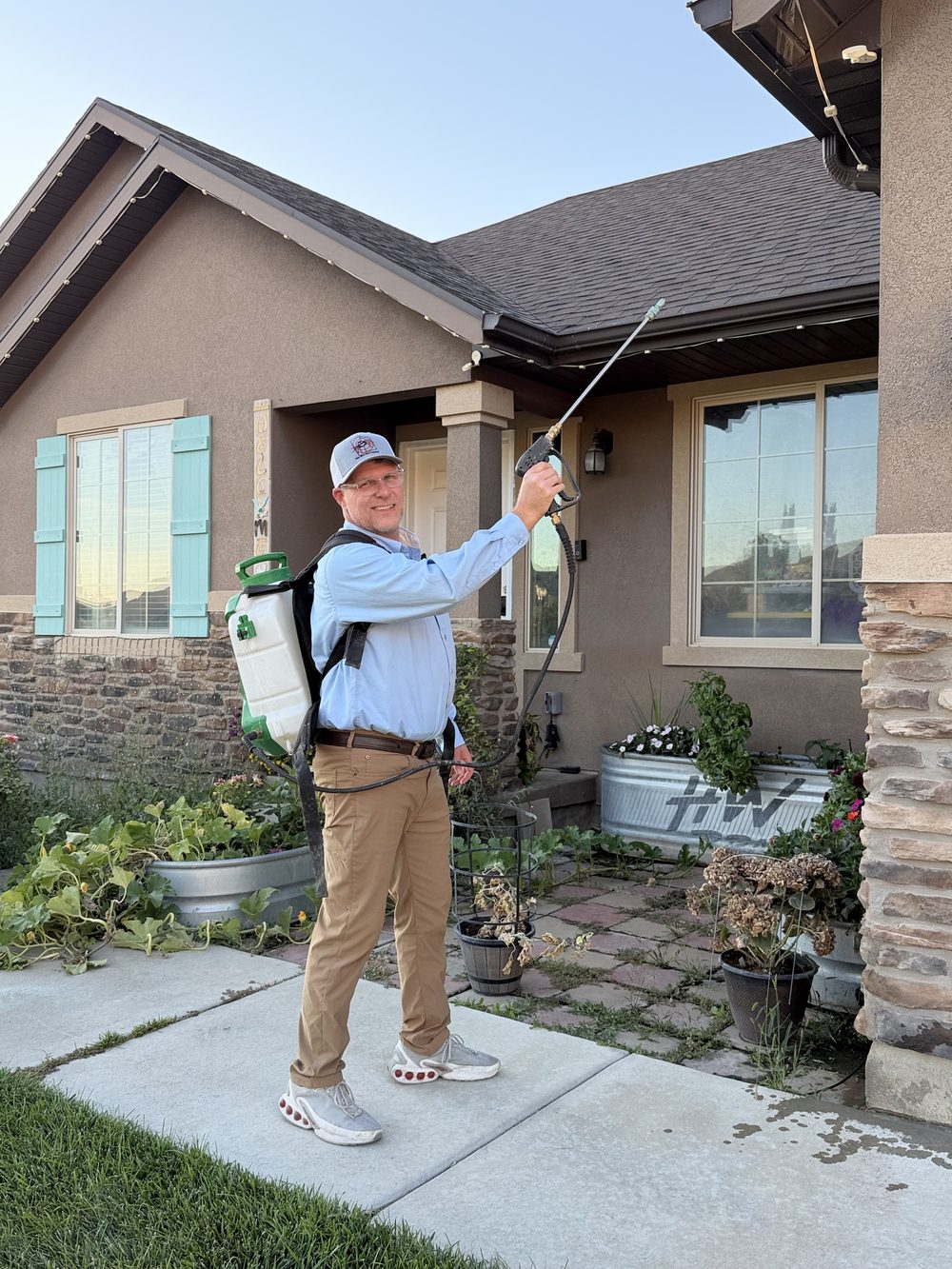 One Shot Pest Control technician spraying under the eaves of a Utah home