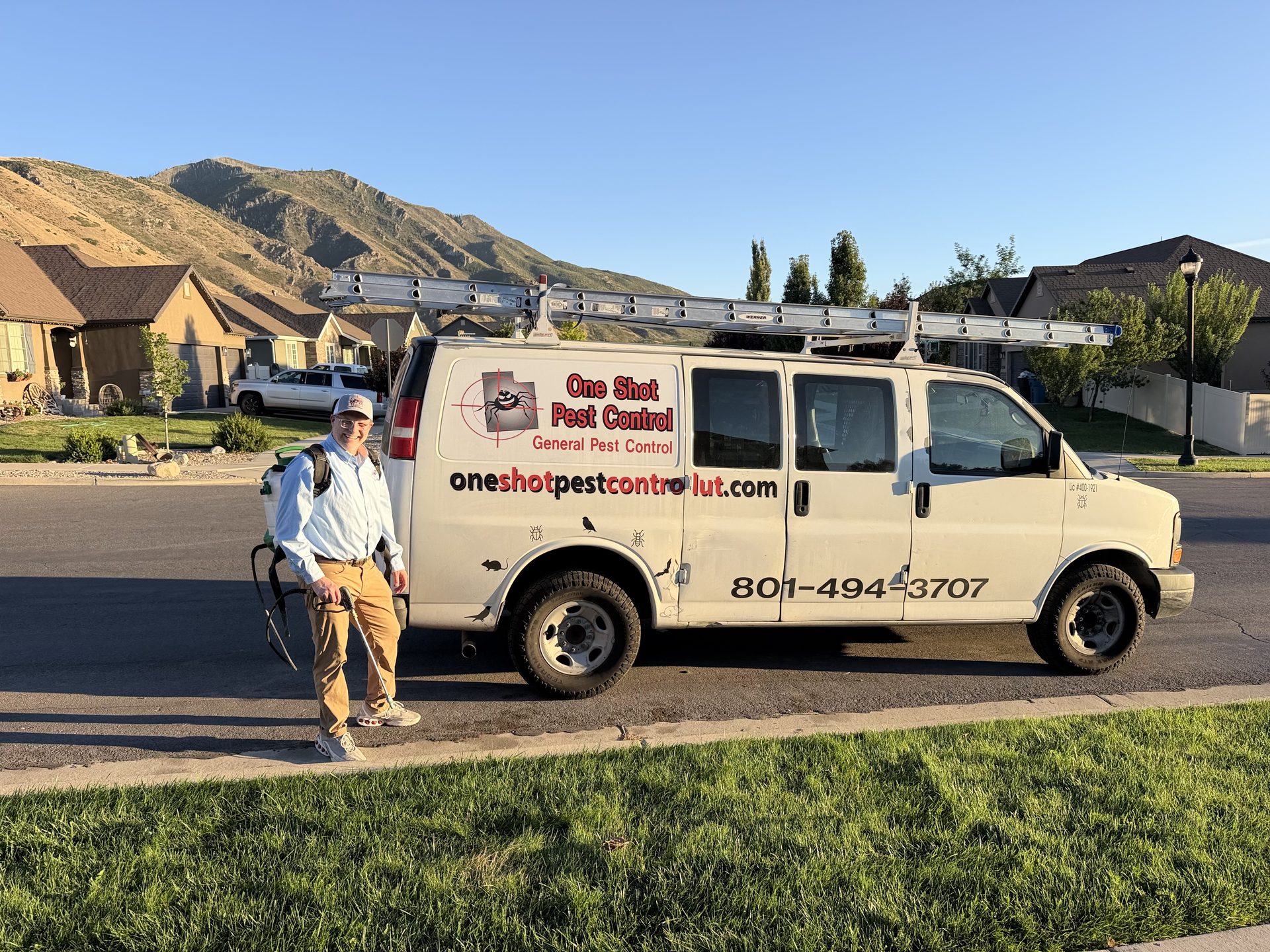 One Shot Pest Control service van parked on a Payson street with a technician beside it